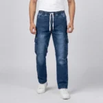 Male model wearing dark blue denim cargo pants with text callouts indicating an integrated drawstring, distressed thighs, and dual cargo pockets.