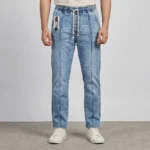 Male model wearing men's light blue elastic waist denim pants featuring a front leg seam, slip pockets, and a drawstring.
