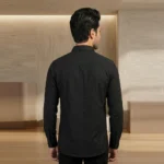 Back view of a male model wearing a men's black textured button-down shirt, showing a tailored fit, a back yoke, and a curved hem.