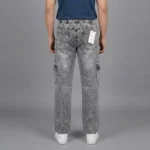 Back view of a male model wearing relaxed fit grey wash denim cargo pants, showing an elastic waistband and classic rear patch pockets.