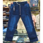 Medium wash denim drawstring pants with front seams held up in a retail shop environment.
