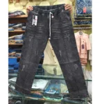 Charcoal black denim pants held up in a store setting, displaying the white rope drawstring, front vertical seams, and subtle distressed details.