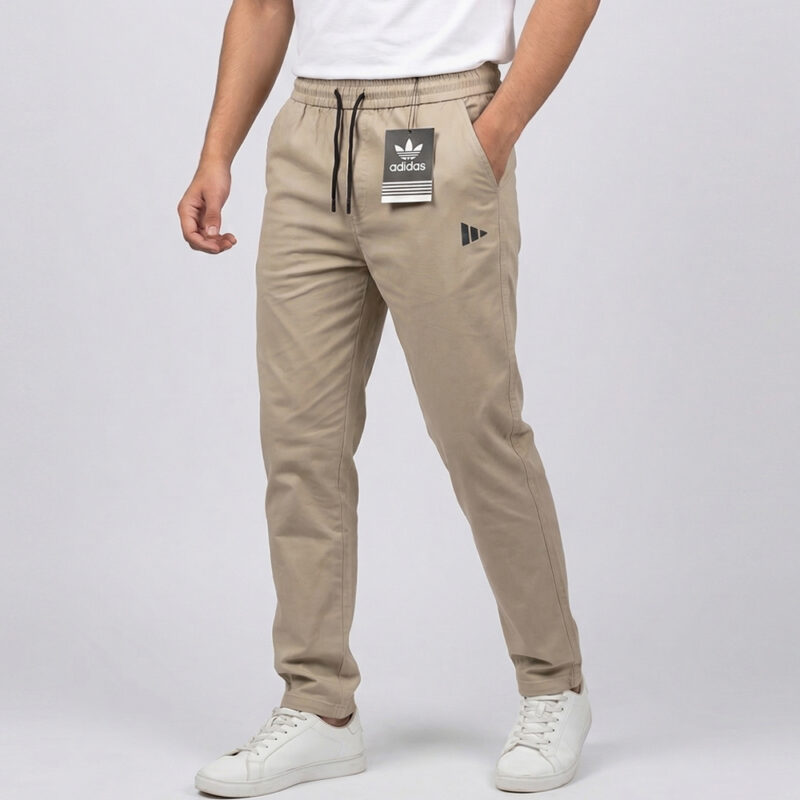 Men's beige Adidas cotton trousers in Pakistan featuring a slim fit, elastic drawstring waist, and black branding detail.
