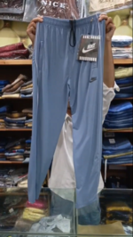Light blue Nike trousers for men in Pakistan with white side piping, zipper pockets, and adjustable drawstring waist.