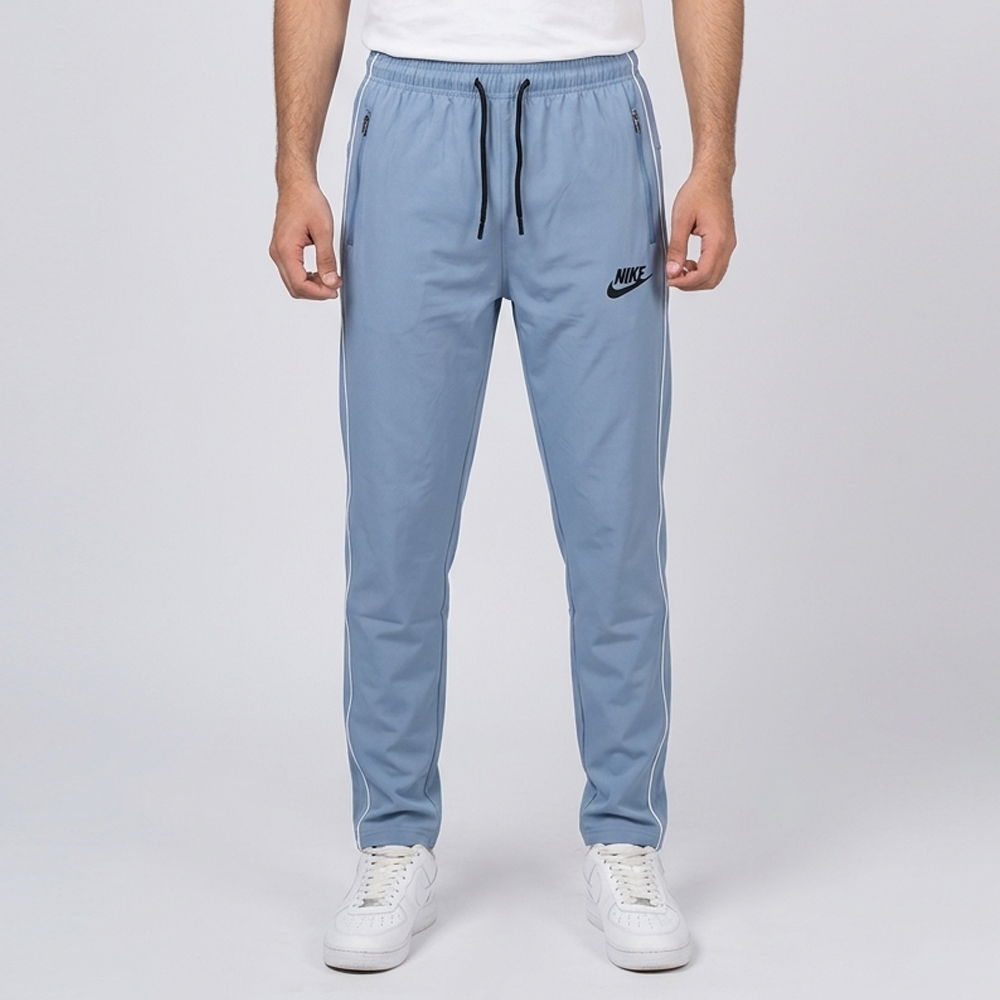 Light blue Nike trousers for men in Pakistan with white side piping, zipper pockets, and adjustable drawstring waist.